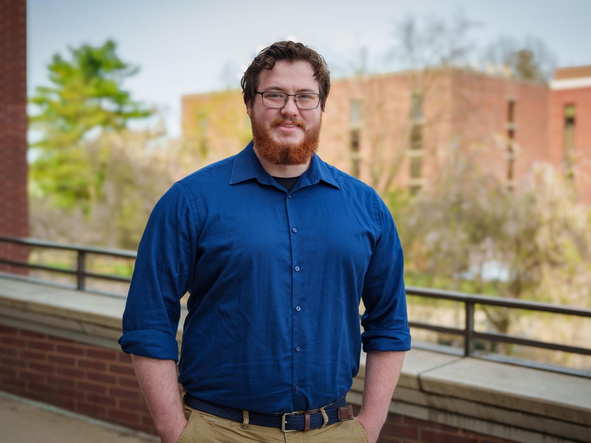 person with red hair and beard wearing glasses and blue shirt