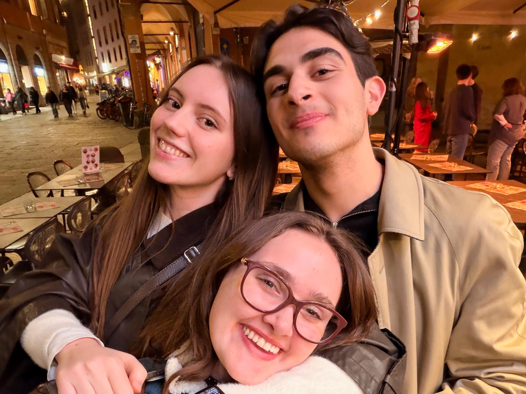 Luscinia Quance wears glasses and stands in front wearing a blue jean jacket as her two friends stand behind her. 