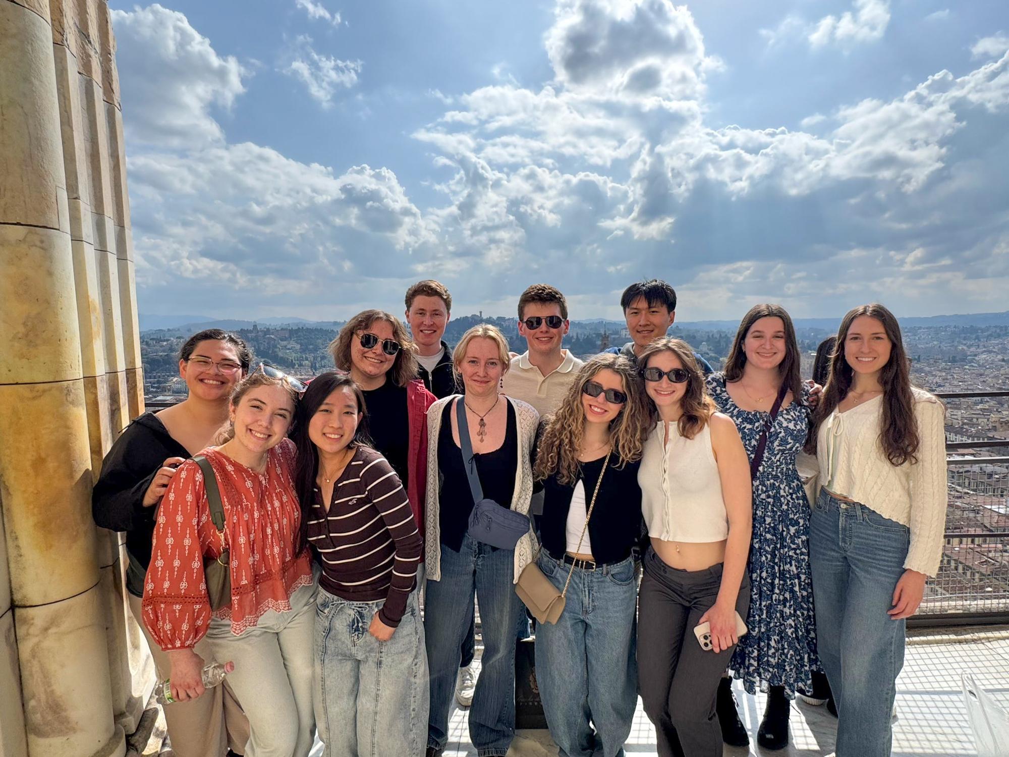 Students stand in a group, a lot of sky in the background, in front of the Cathedral of Santa Maria del Fiore in Florence. 