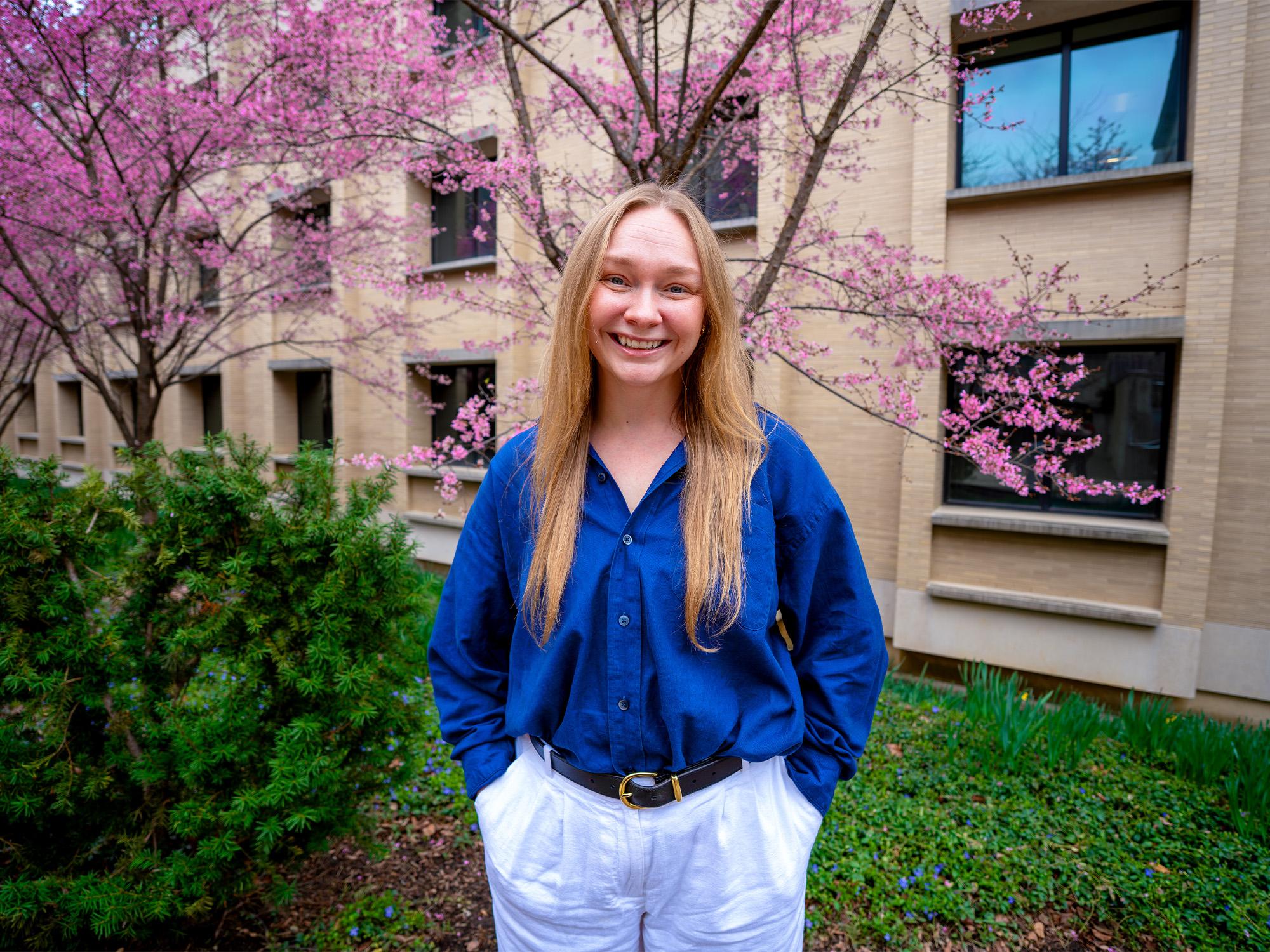woman in front of flowering tree and building