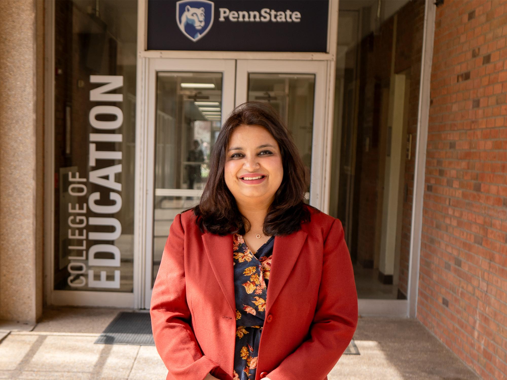 woman in front of college of education and penn state signs