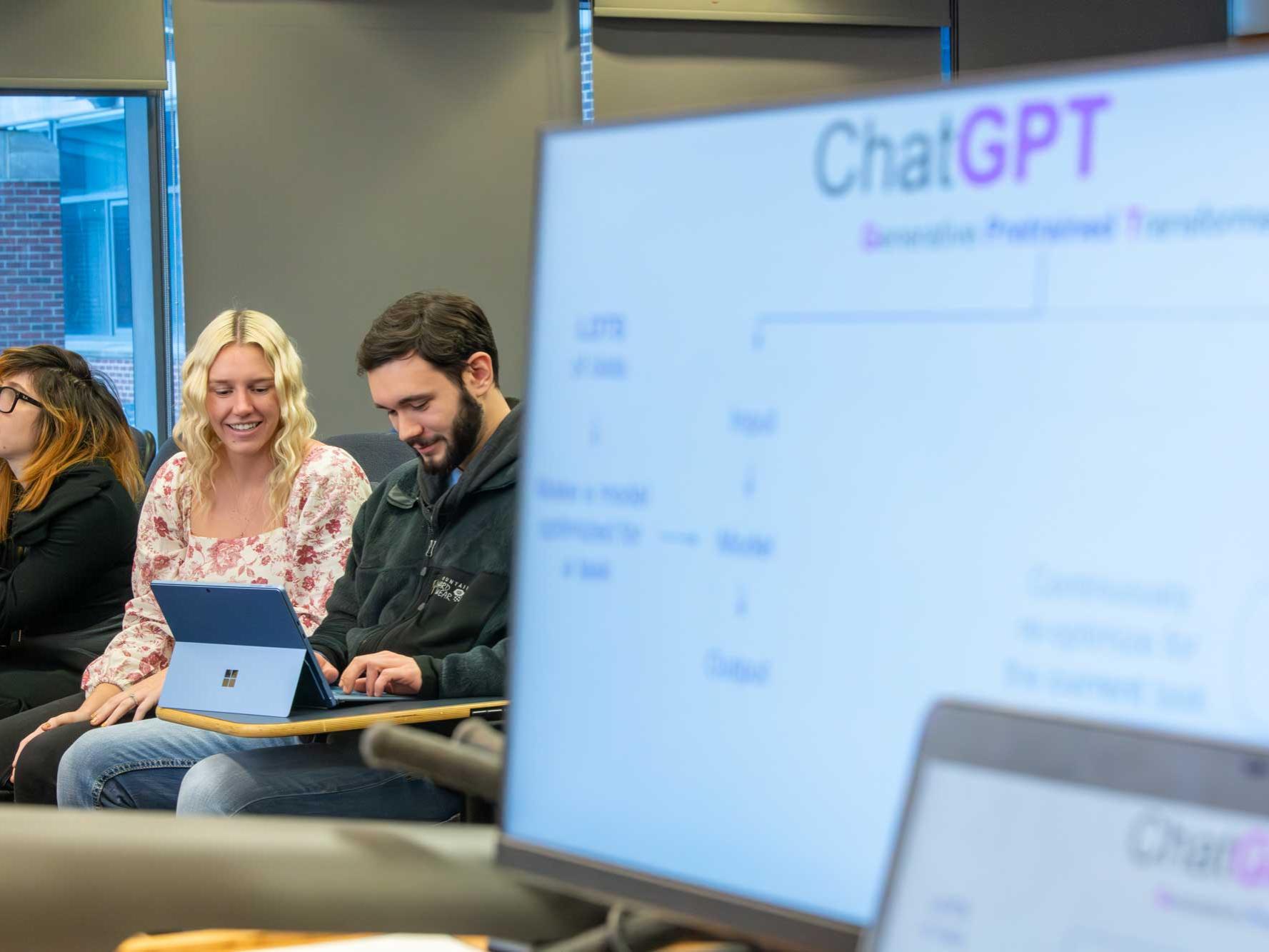 Computer with slide titled chatGPT in foreground with Morgan Vincent and others sitting in background