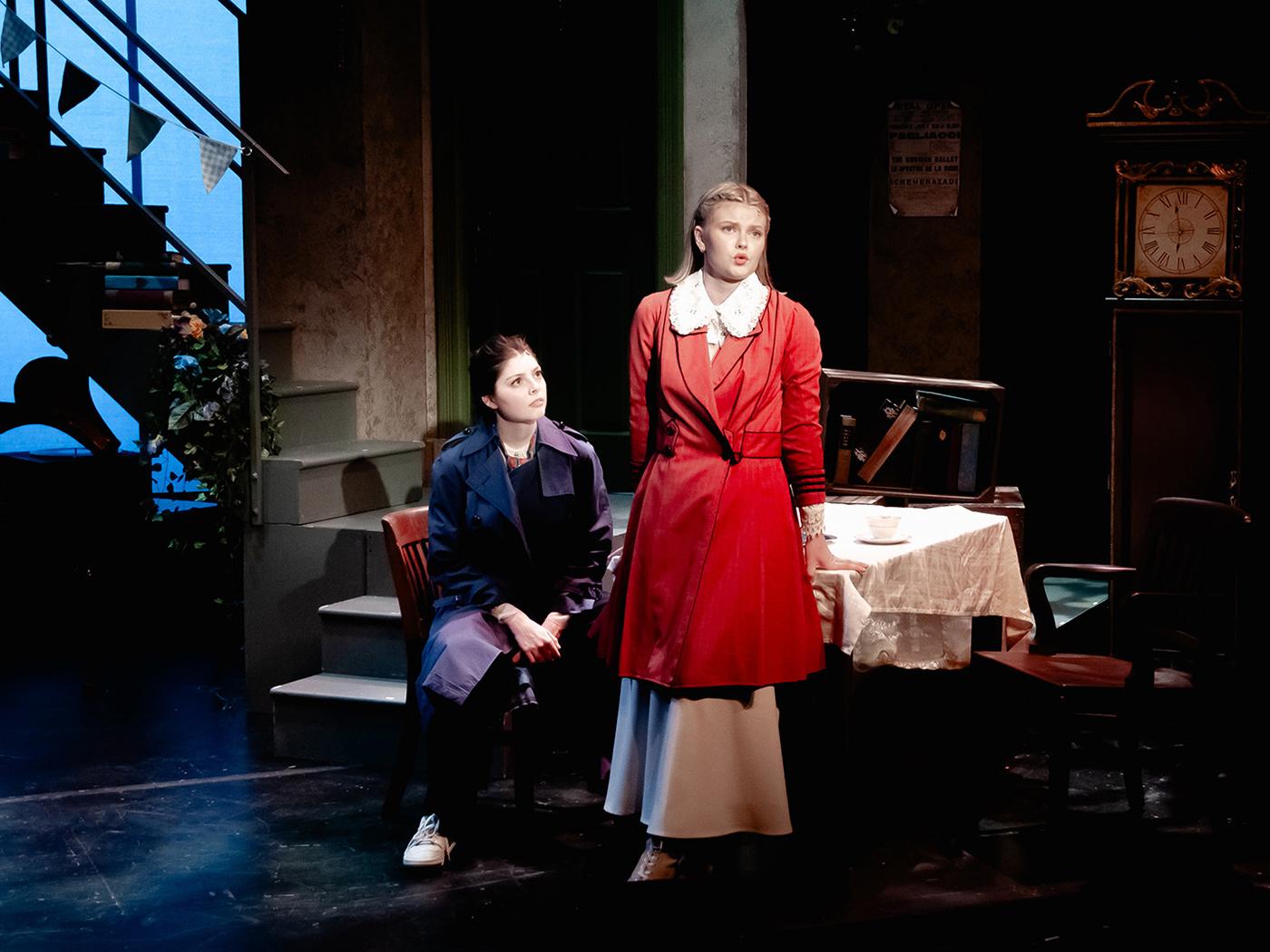Two actors perform on a stage, one is singing