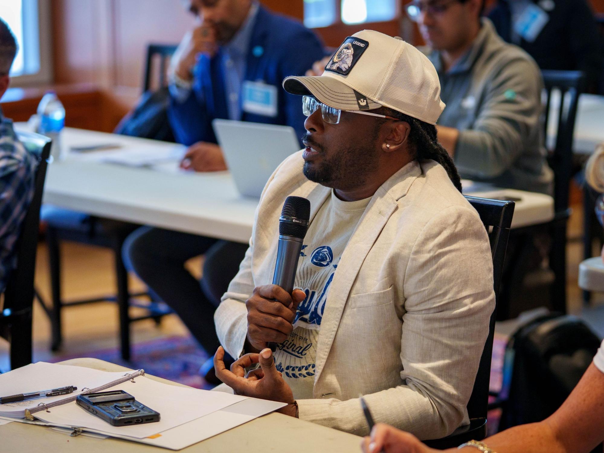 person in ball cap speaks into microphone