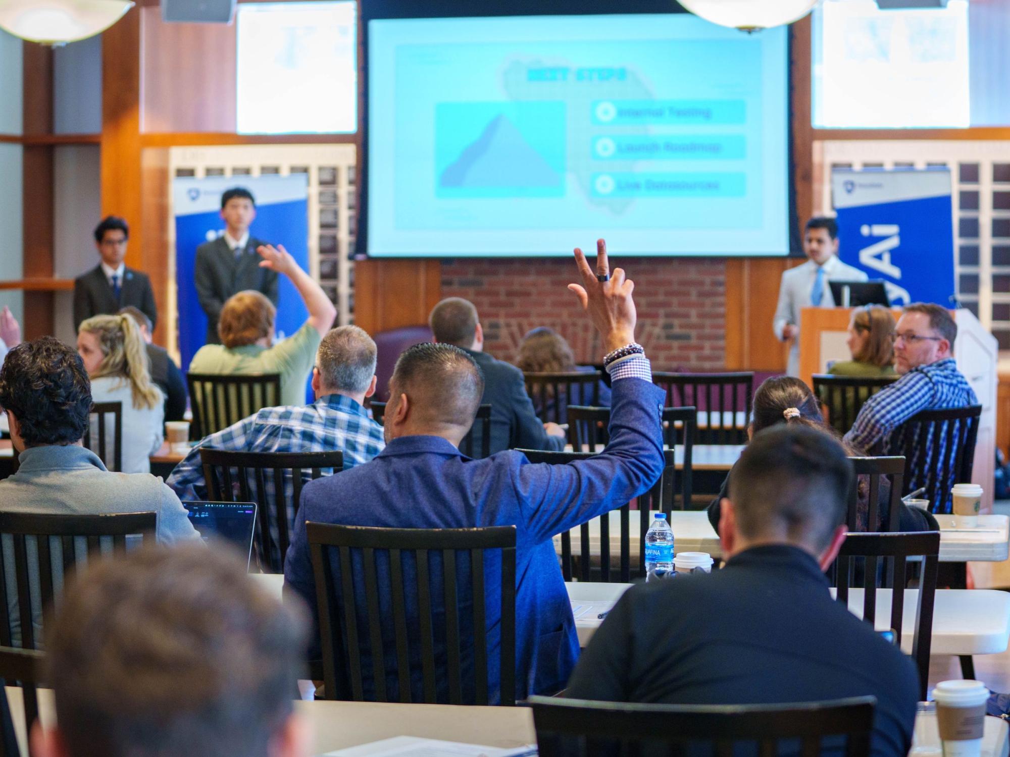 conference attendees raise hands to question presenters