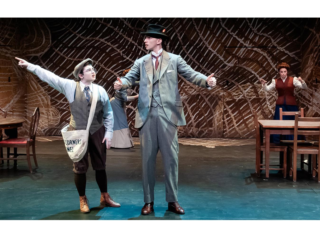 A newsboy points off into the distance for a man wearing a suit and hat, and a woman is in the background standing at a table