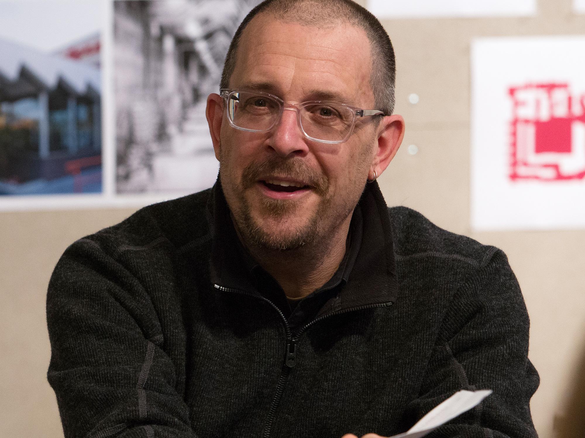 A man wearing glasses and a dark shirt.