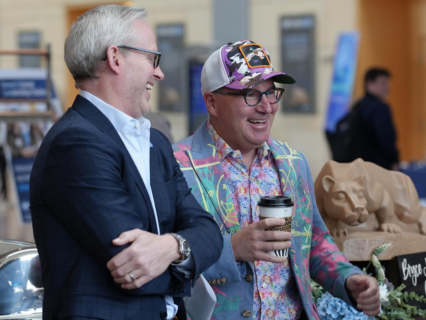 Corey Phelps and Dan Ives, who is holding a cup of coffee, share a laugh.