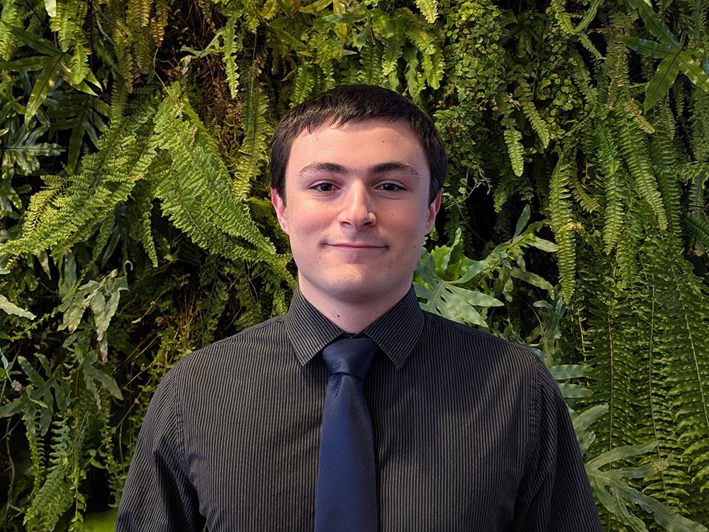A young man wearing a dark dress shirt and tie.