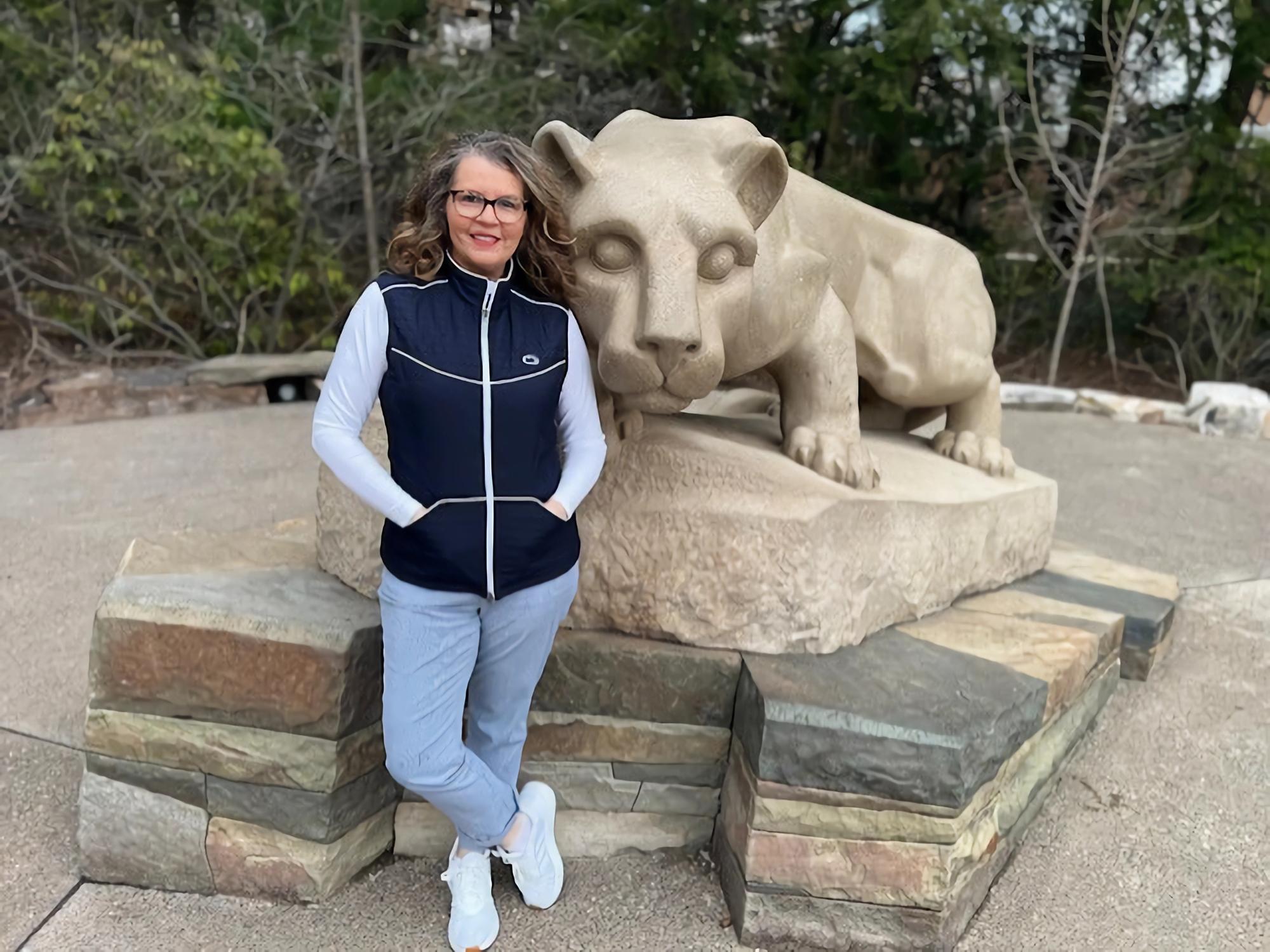 A woman standing in front of the Nittany Lion Shrine at Penn State University Park.