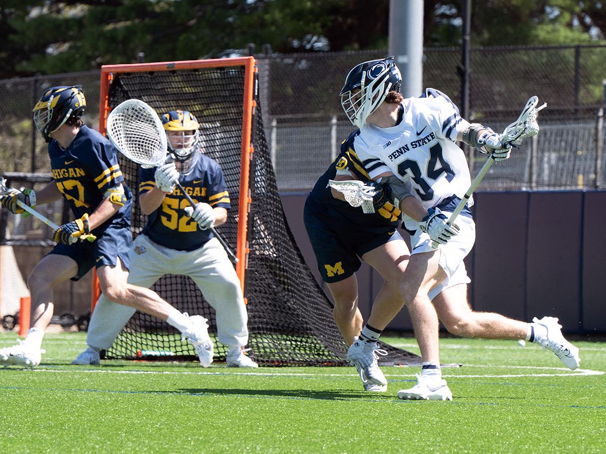 Penn State player tries to maneuver around defender with goal in the background