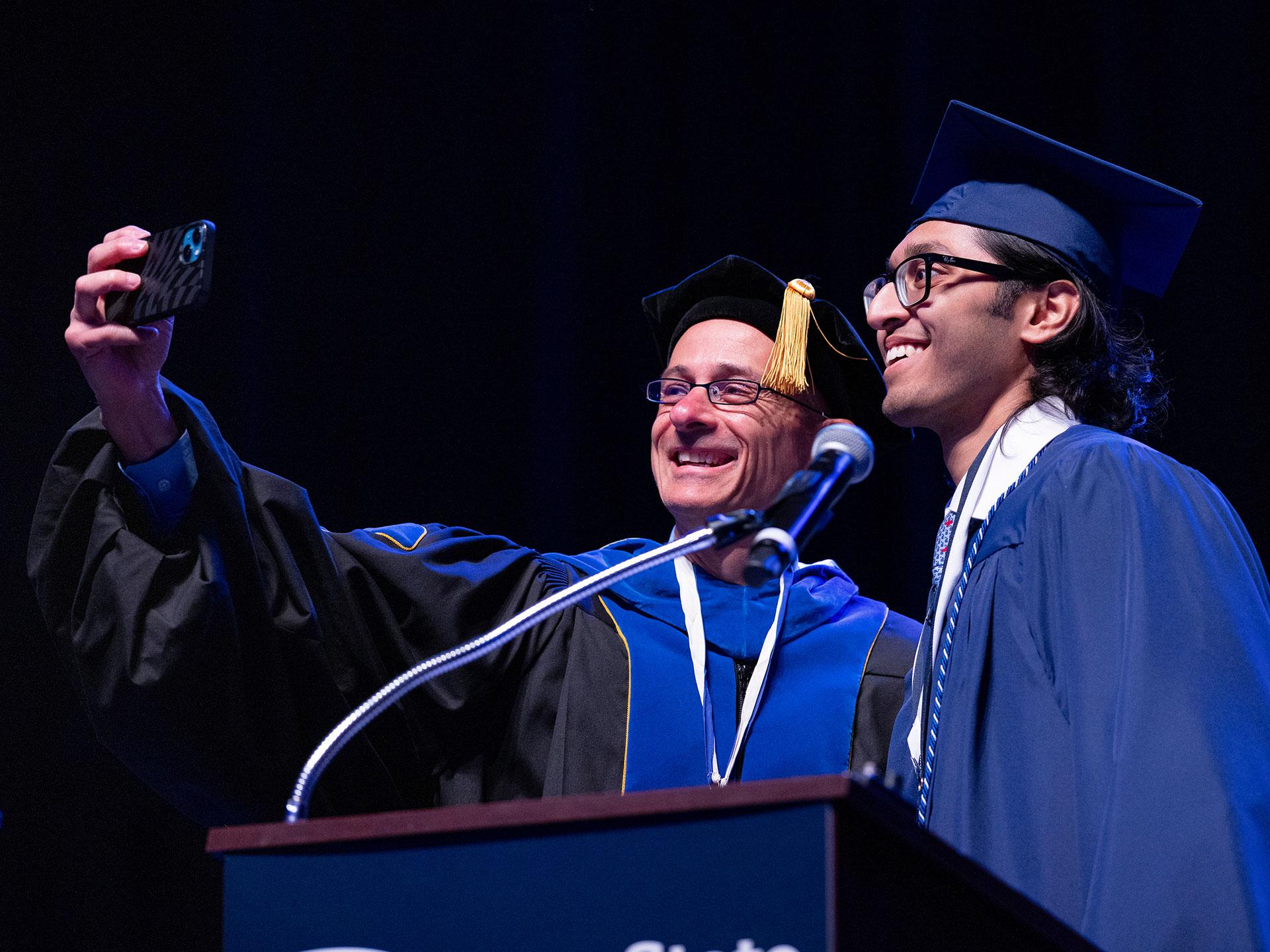 two men in caps and gowns posing for a selfie