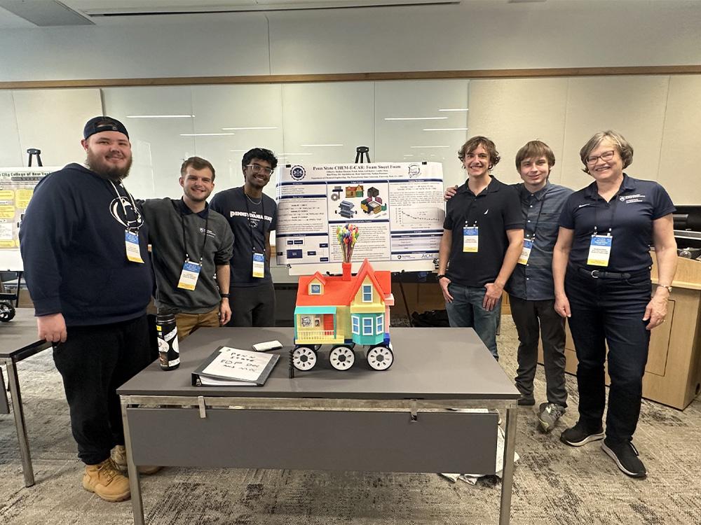  Penn State Chem-E-Car team members posing with the Foam Sweet Foam car and poster
