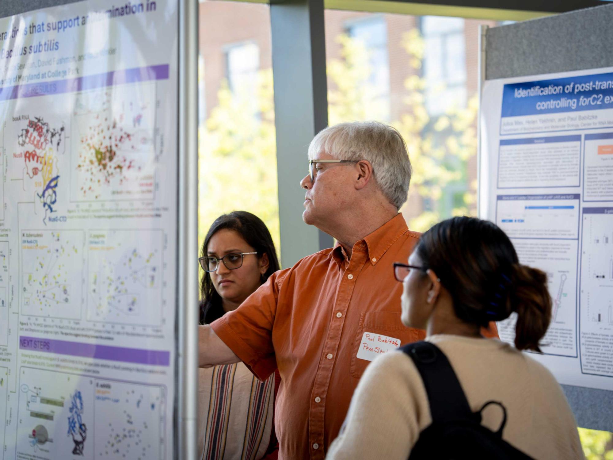 Paul Babitzke points to research poster while others look on