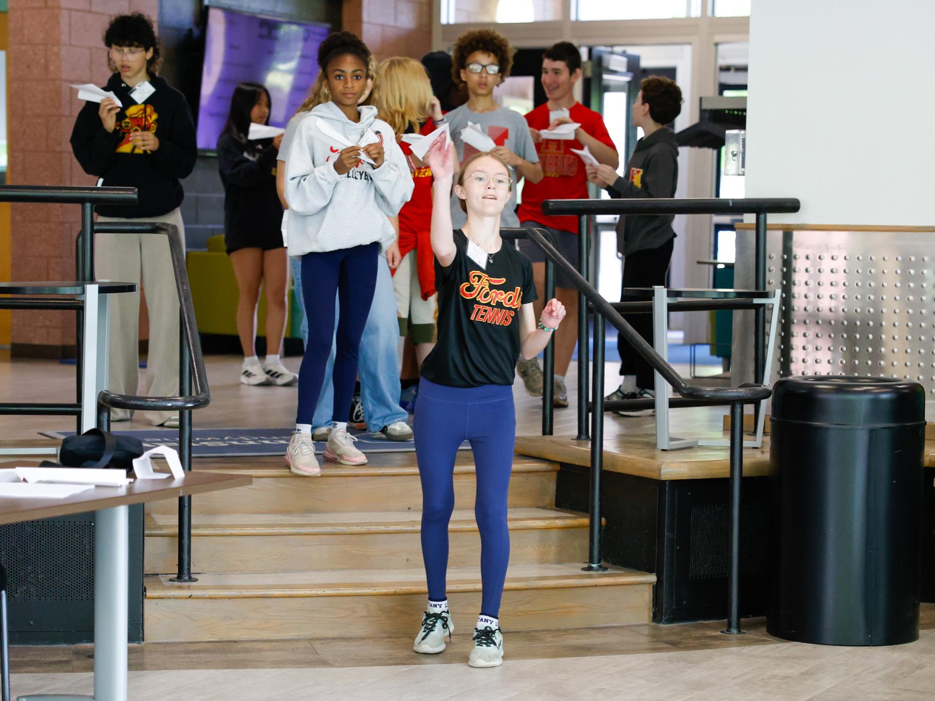 Group of students preparing to fly paper airplanes on the steps of the Tomezsko Lounge. 