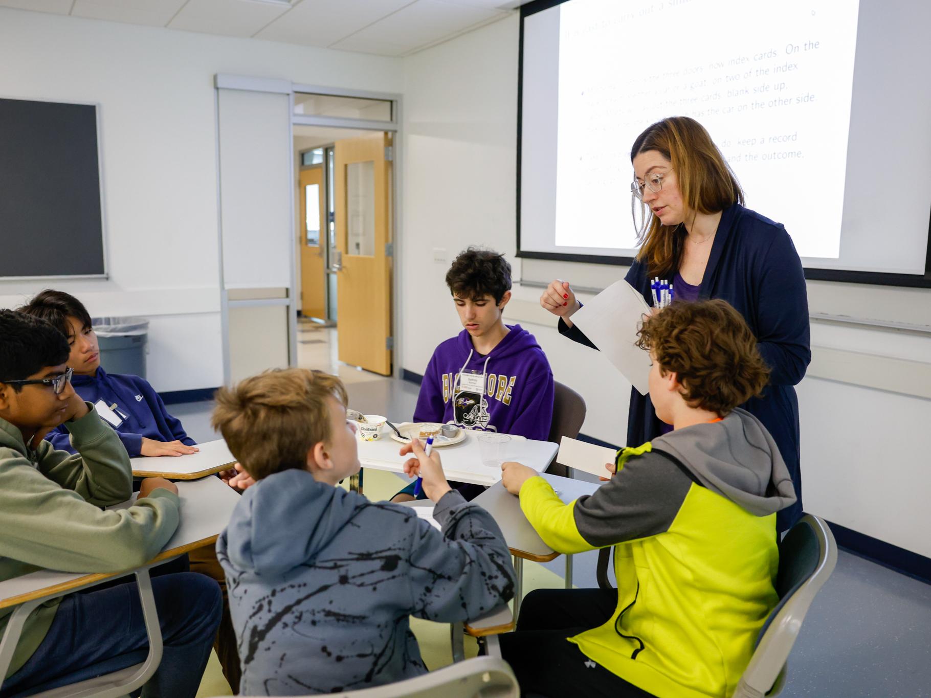 Marina Skyers giving students papers for a probability workshop. 