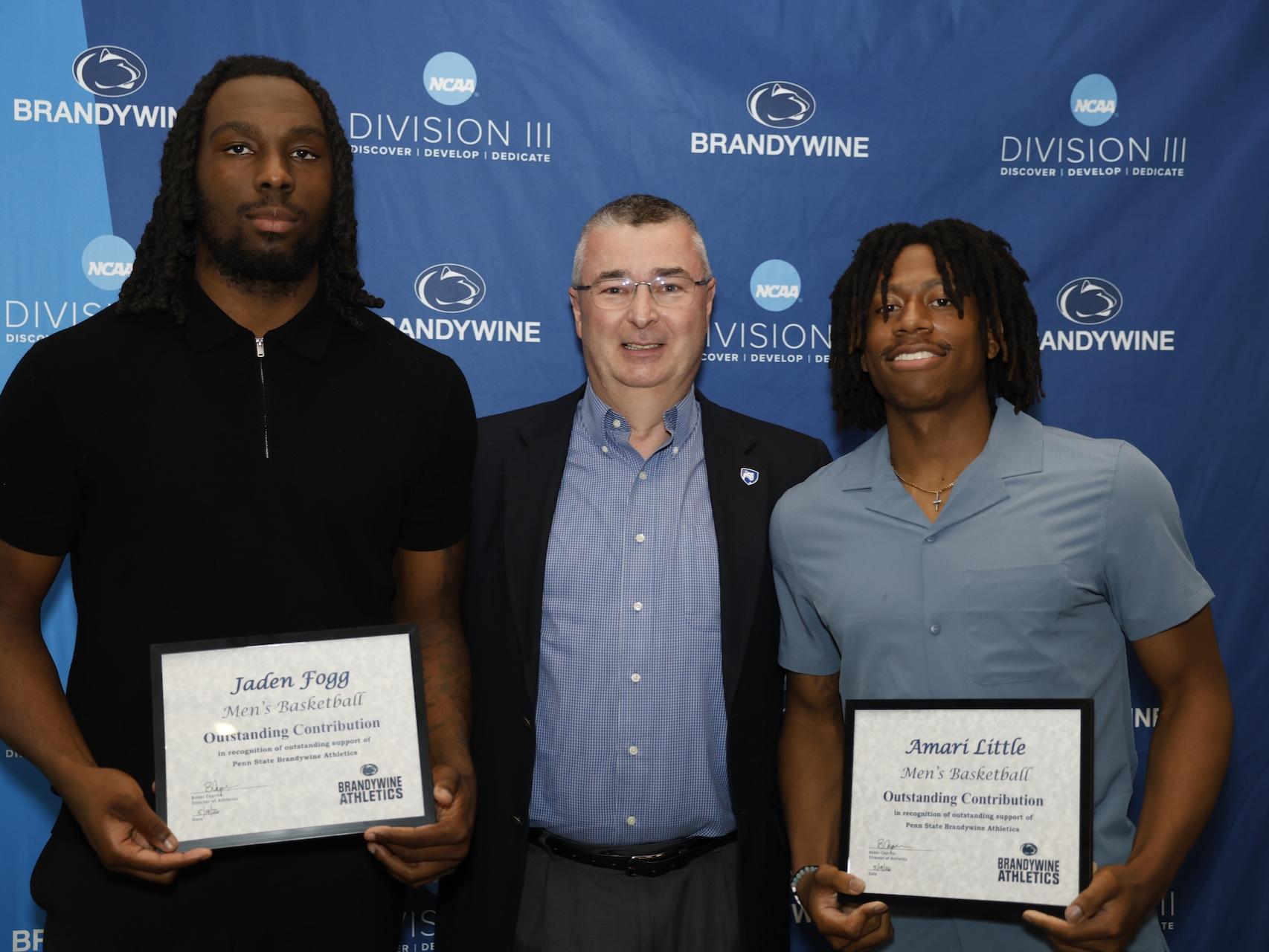 two students holding certificates with director of communications
