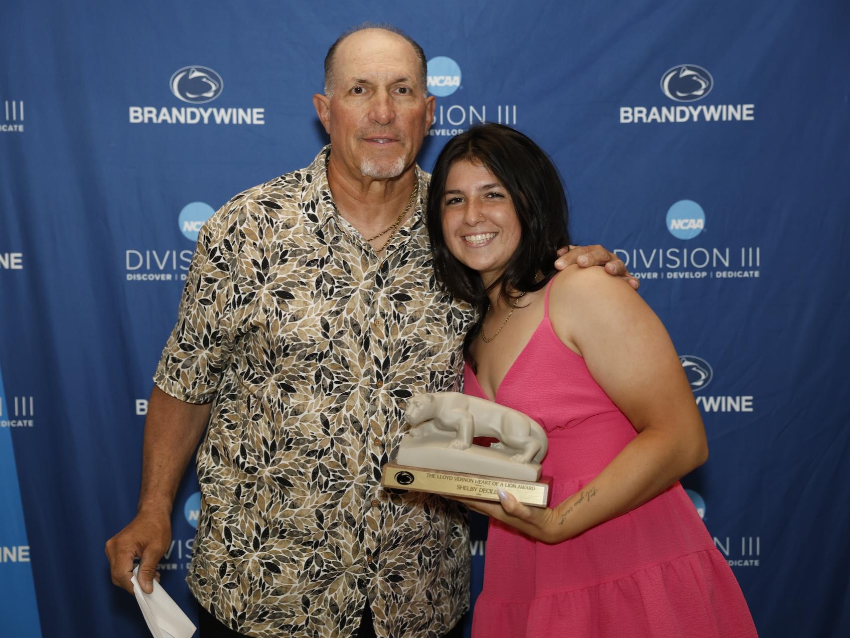 student holding lion statue with her coach