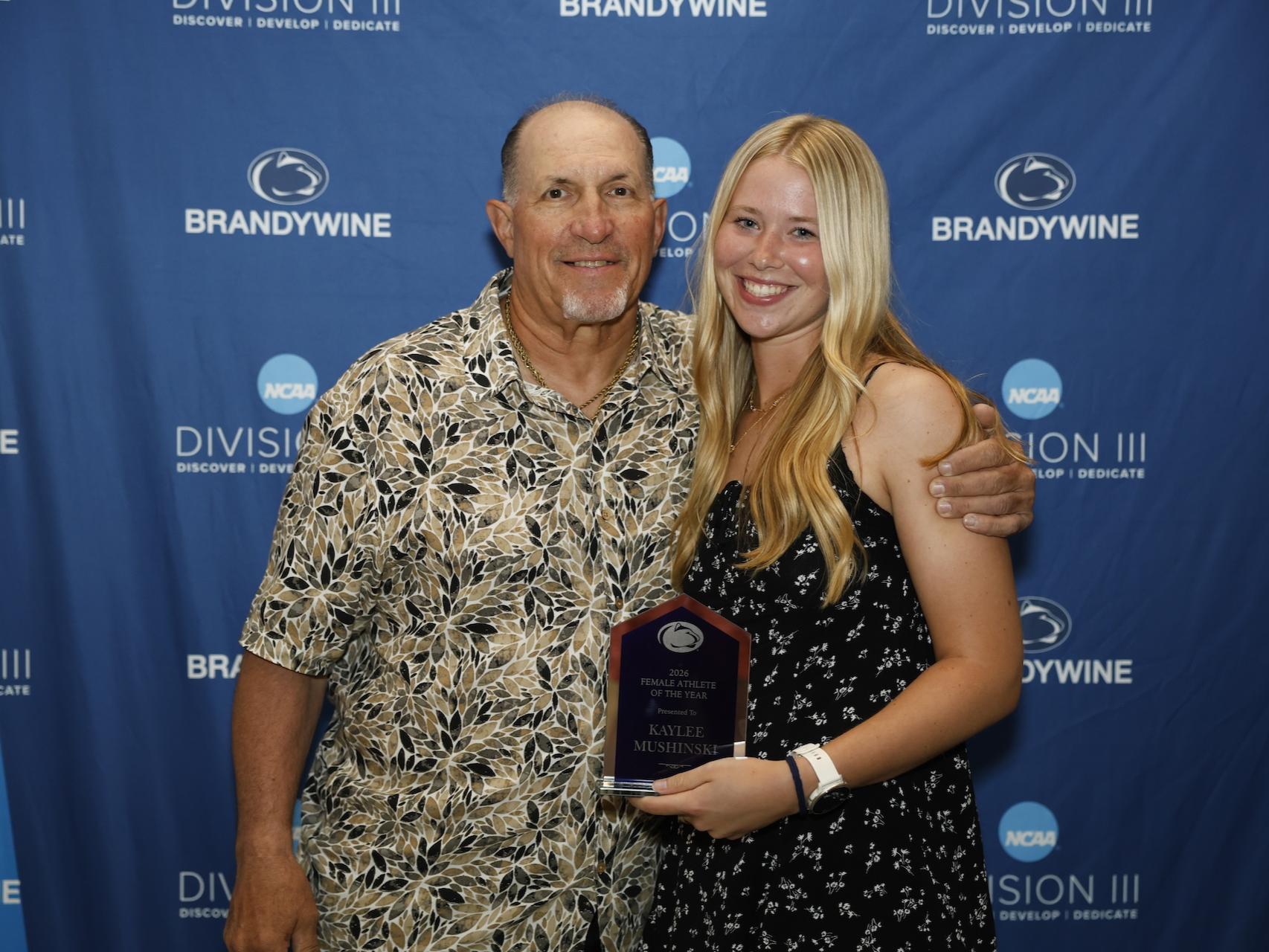 student holding plaque with coach