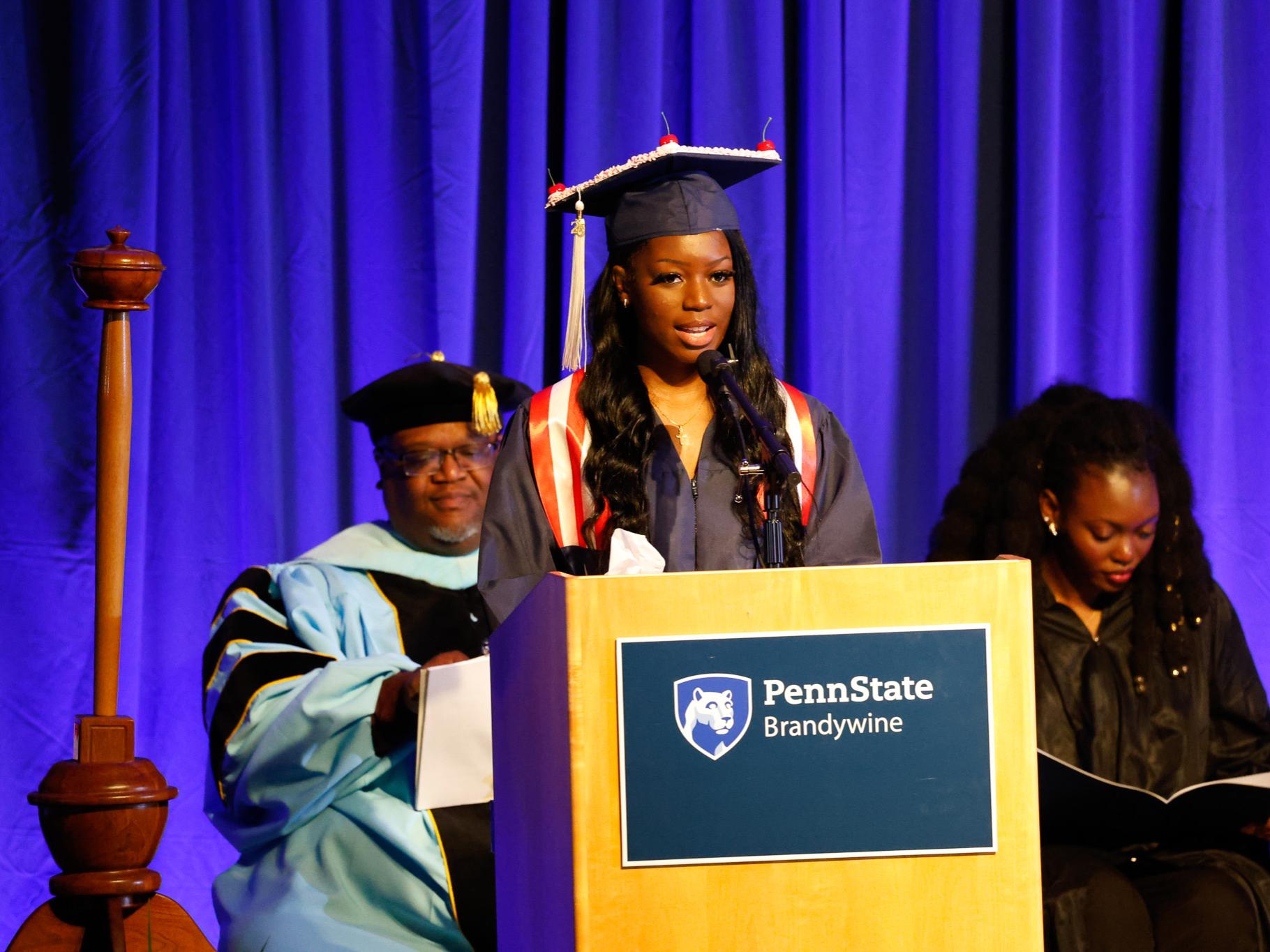 Shiline Varpilah speaking at a podium in a cap and gown