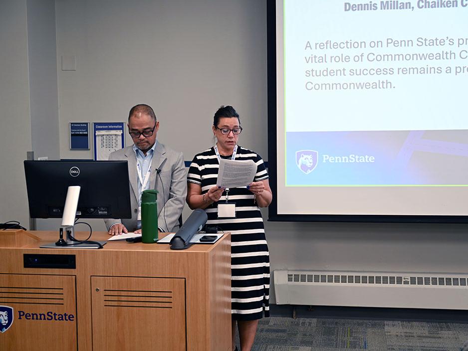 Two people stand near a lecturn and speak.