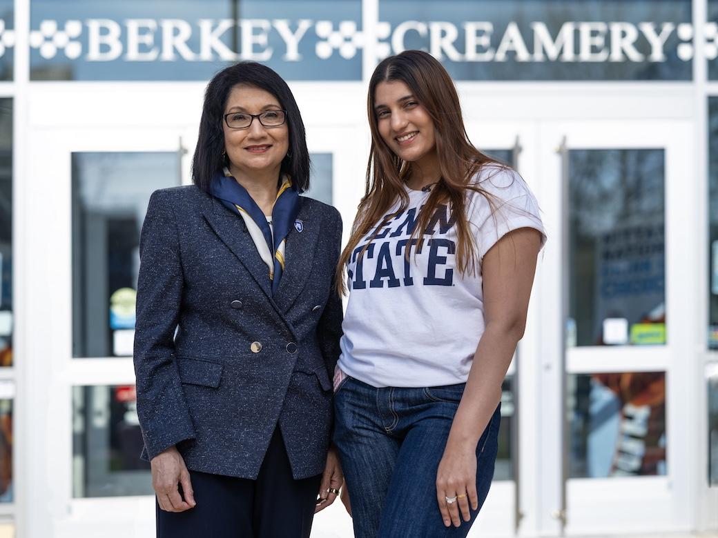Neeli Bendapudi (left) and student Kavishi Halwavala stand together and smile in front of entrance to the Berkey Creamery.
