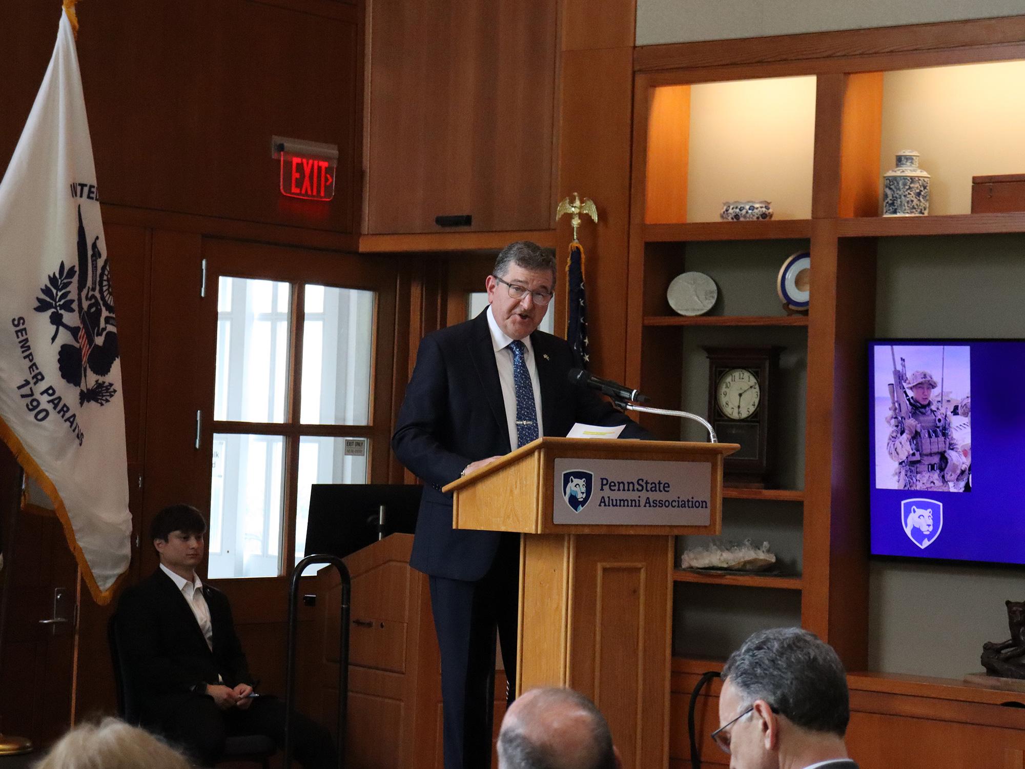 A man wearing a suit speaks at a podium.