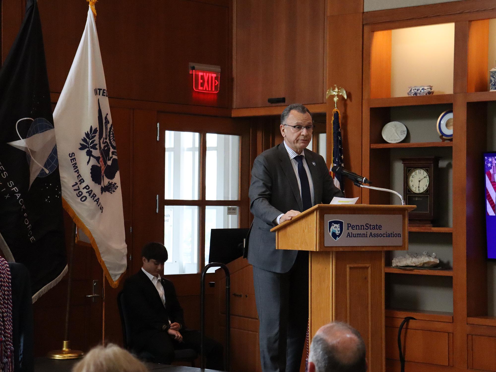 A man wearing a suit speaks at a podium.