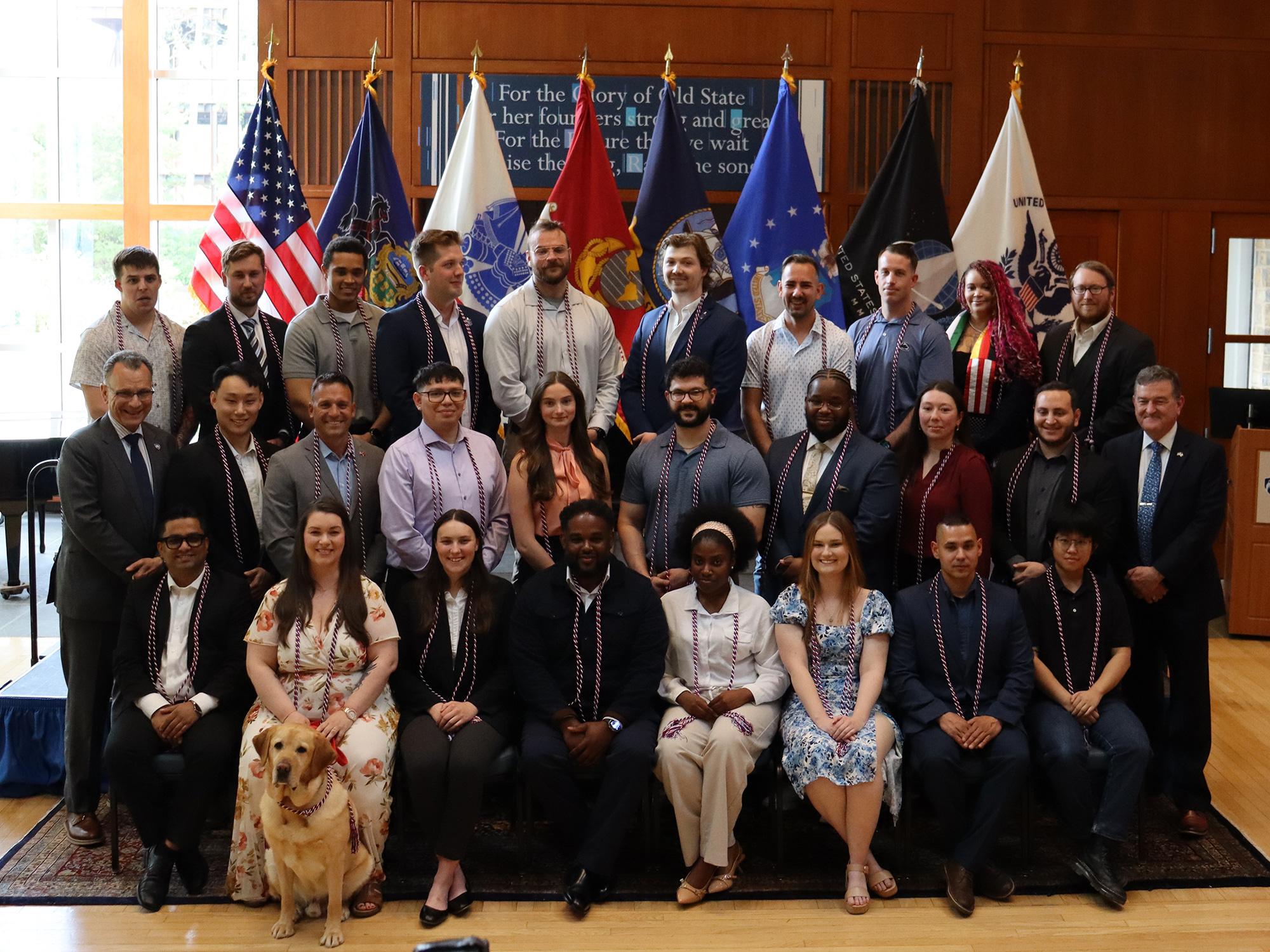 A group of people in a room filled with U.S. military flags.