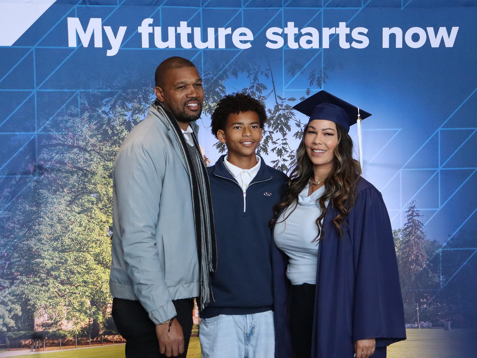 Three people stand in front of a Penn State photo background.