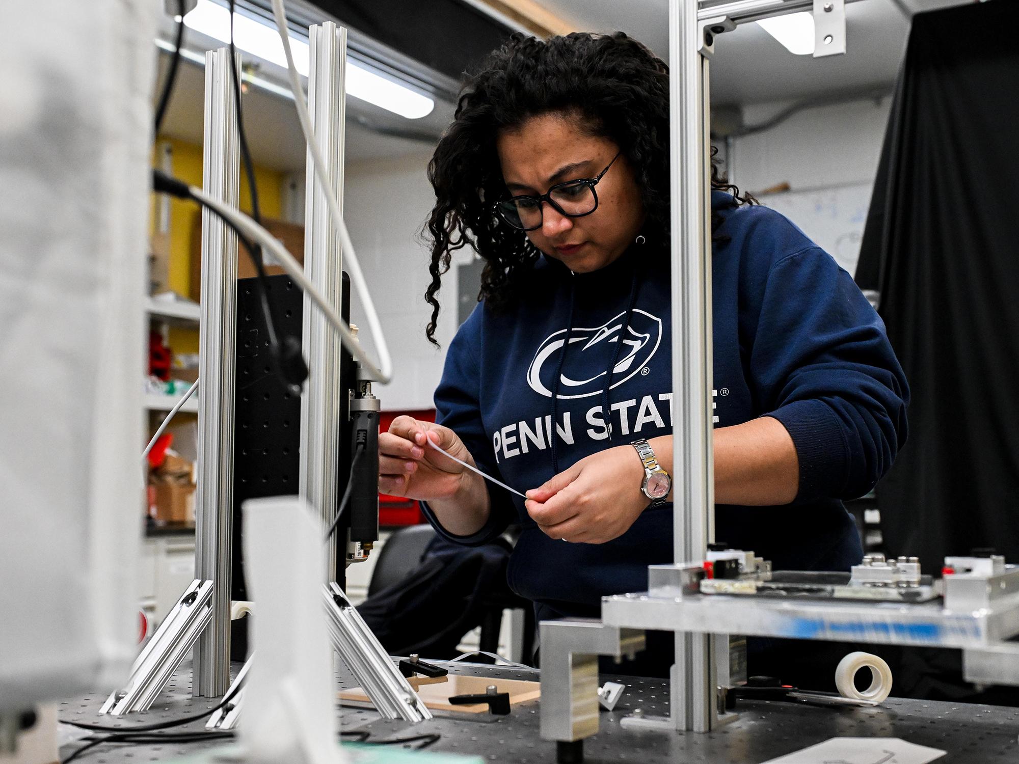 Researcher holding piece of adhesive tape with lab equipment.