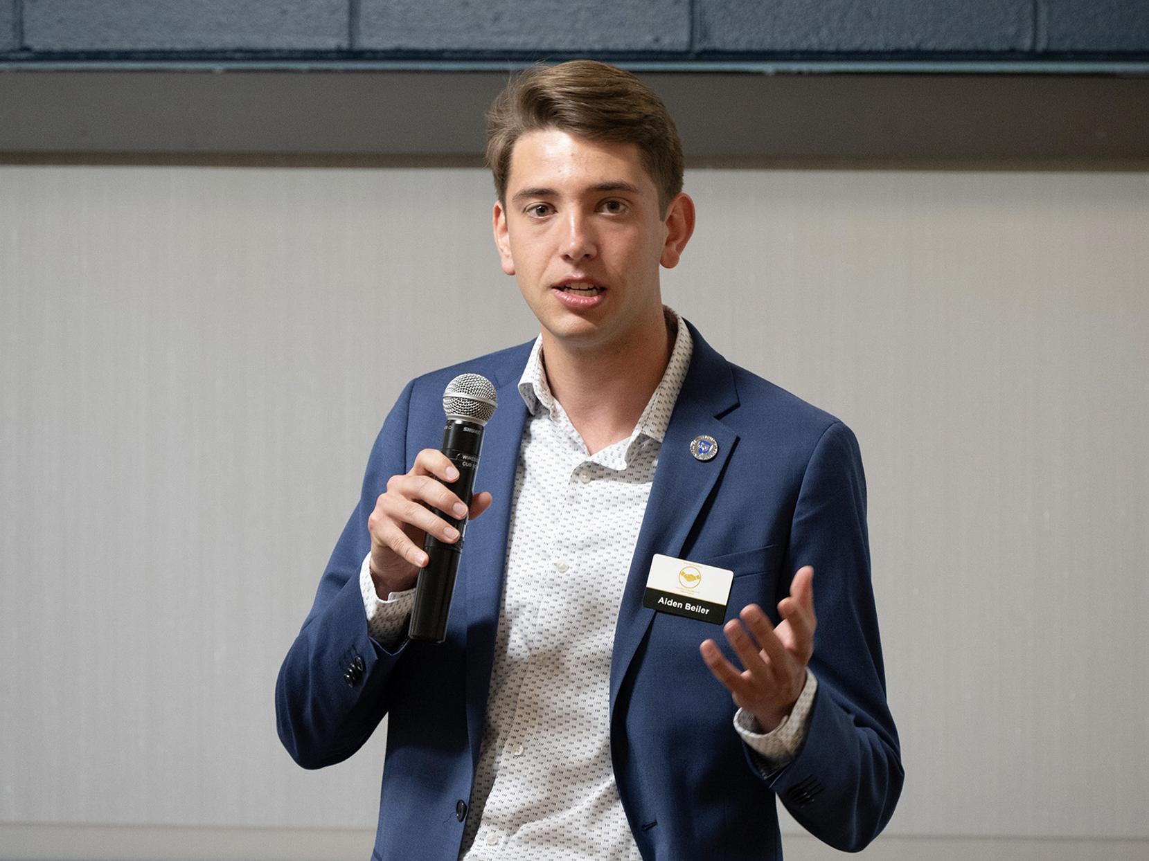 Aiden Beiler speaks into a microphone at an event