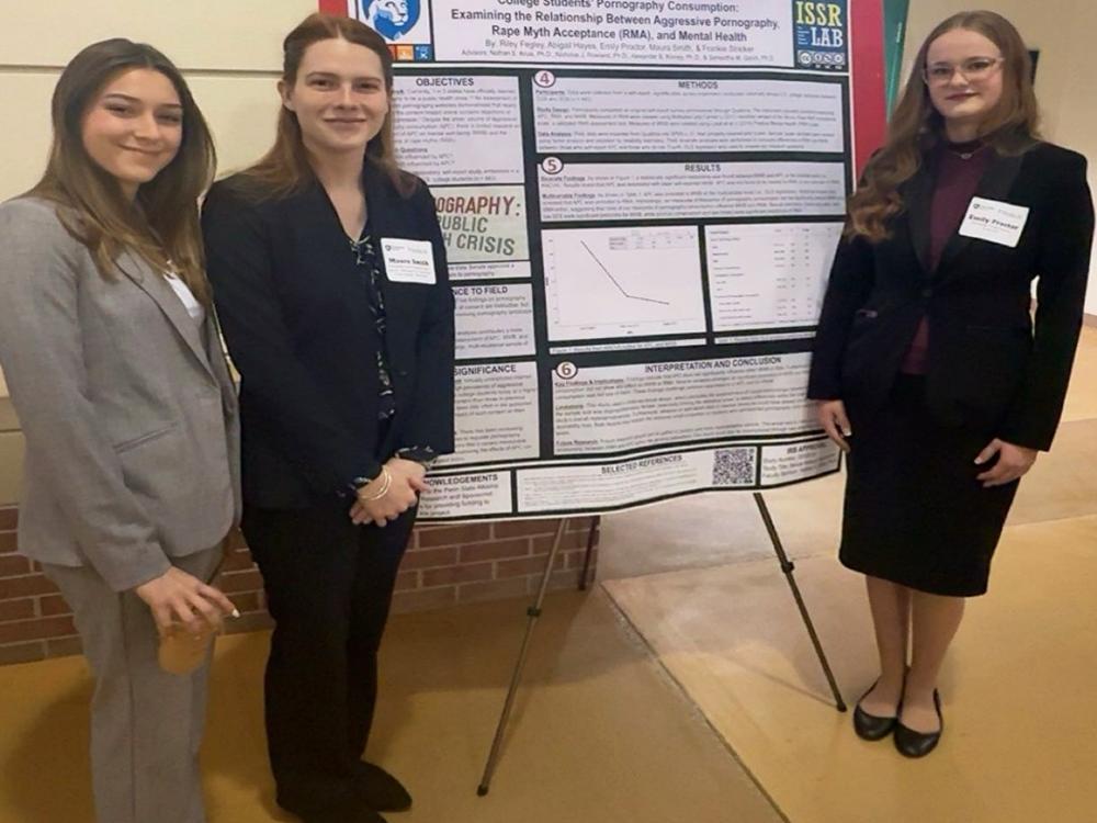 Riley Fegley, Maura Smith, and Emily Proctor stand in front of their research poster