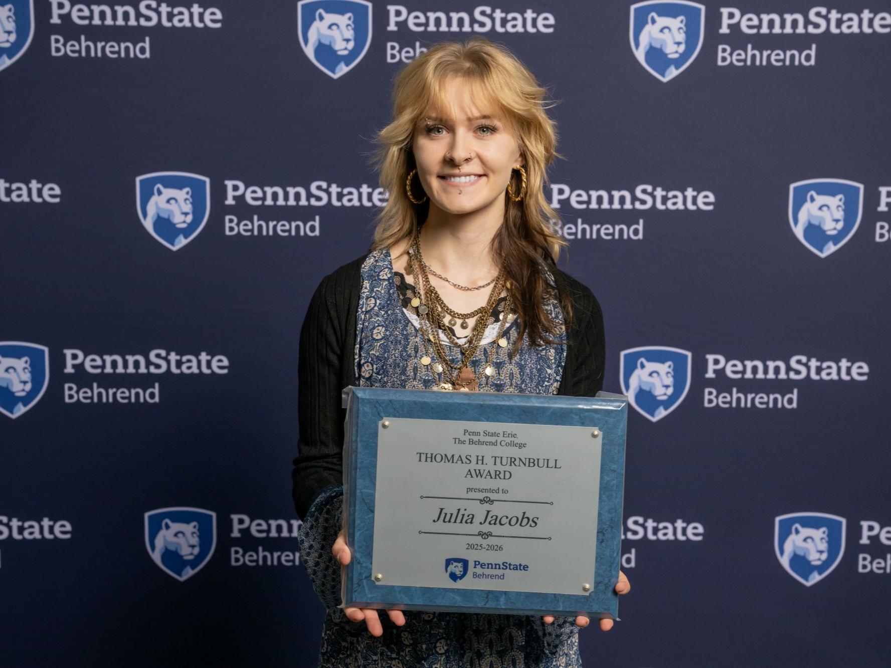 A Penn State Behrend student holds an awards plaque at the college's Honors and Awards Convocation.