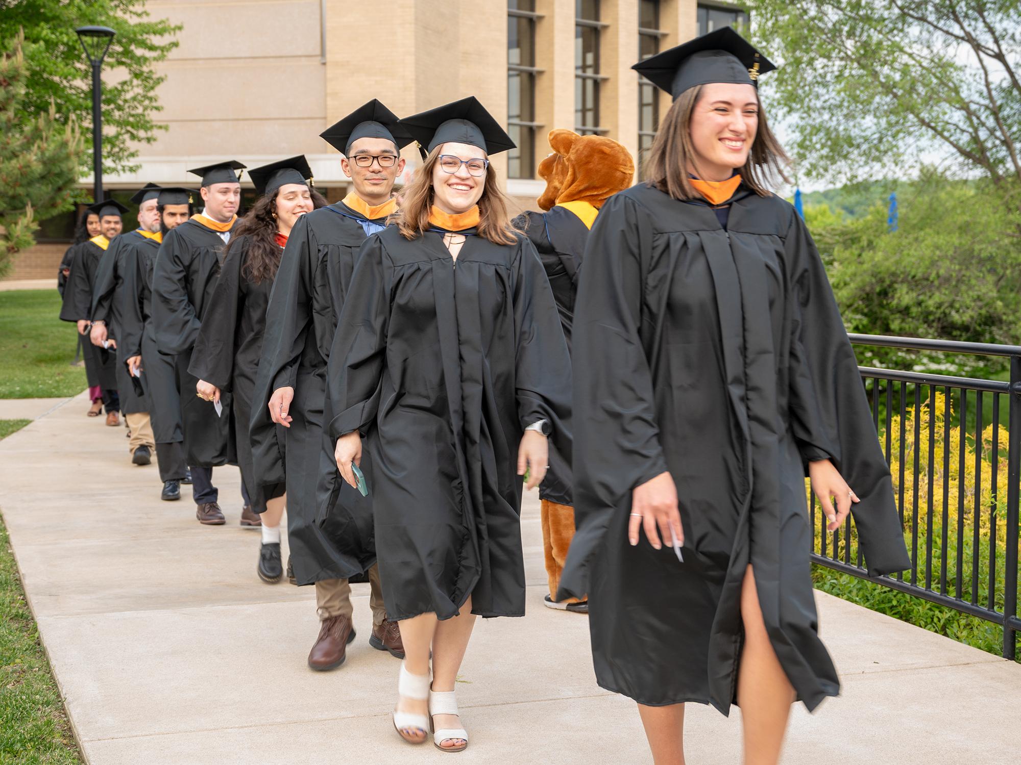 Several students wearing black regalia process toward Penn State Great Valley's 2026 Commencement Ceremony