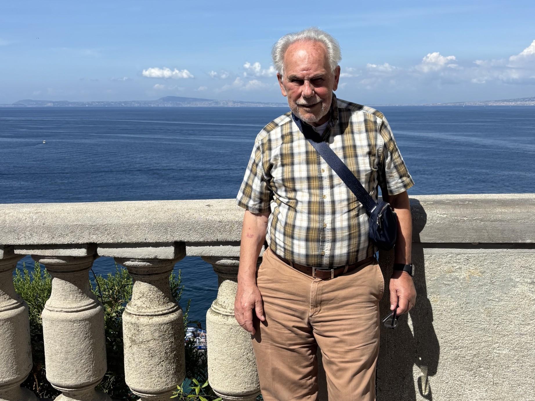 Ron DelPorto stands near a railing in front of a body of water.