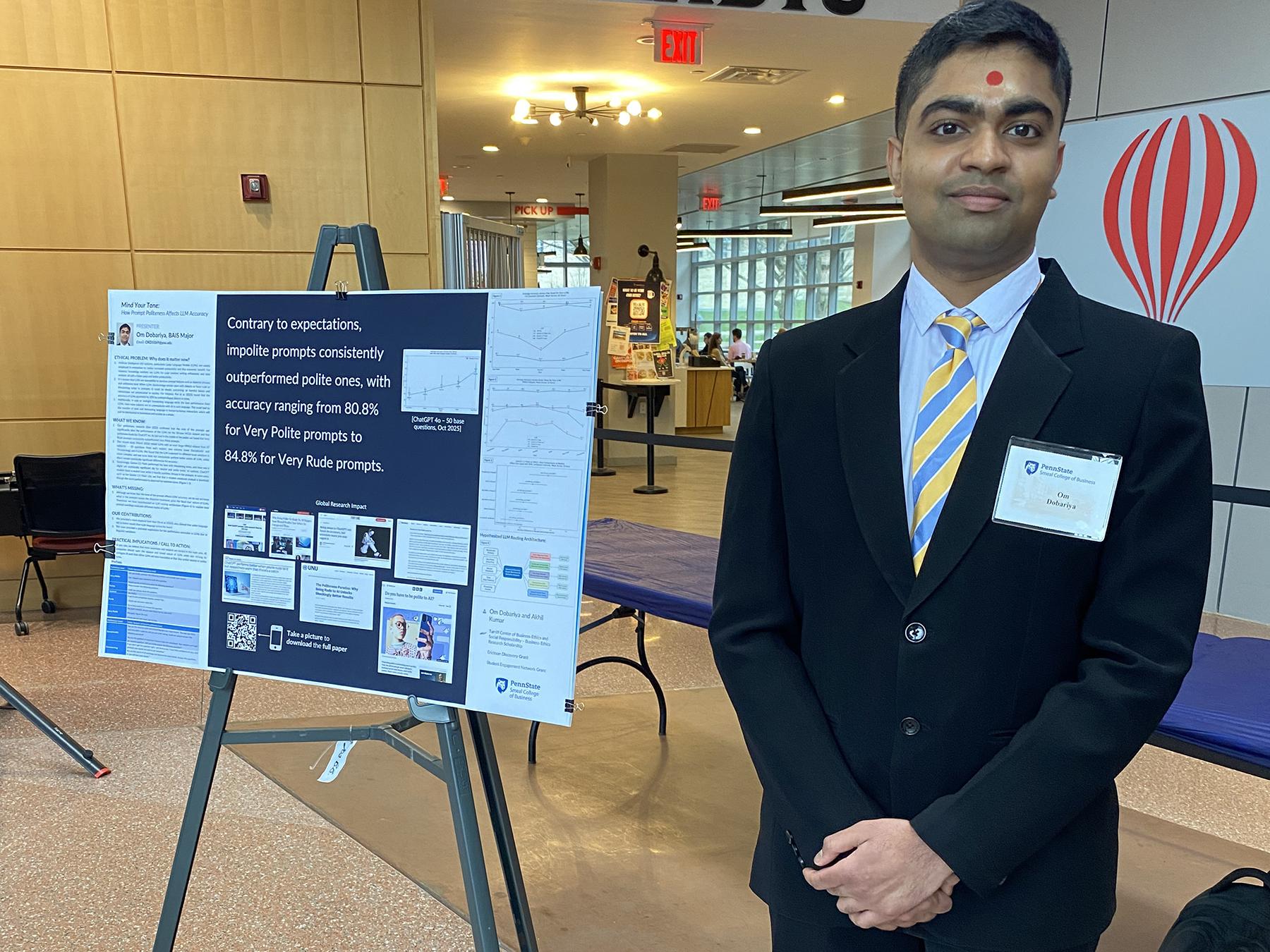 Om Dobariya stands next to a poster presentation of his research.