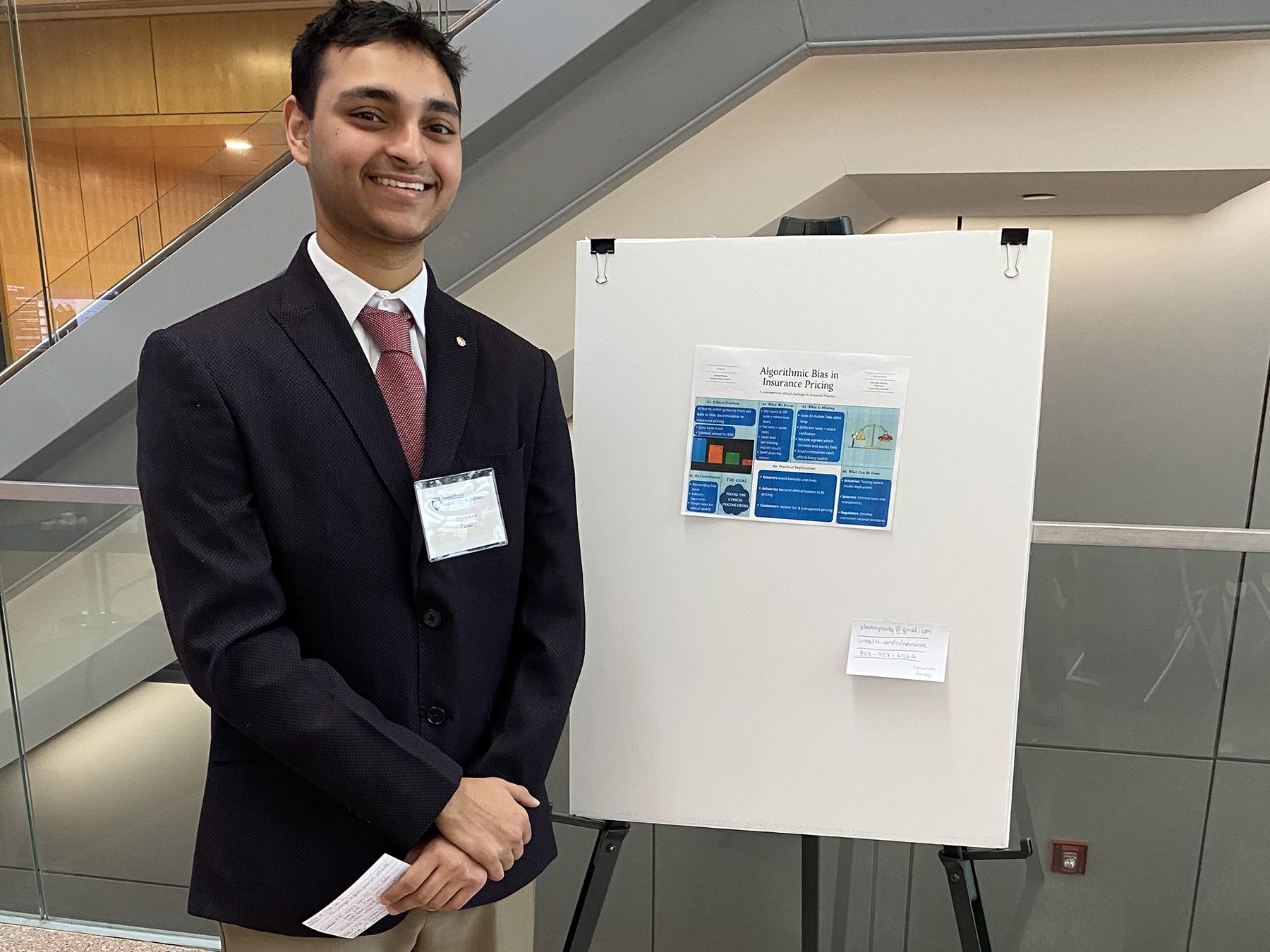Shraman Pandey stands next to research poster.