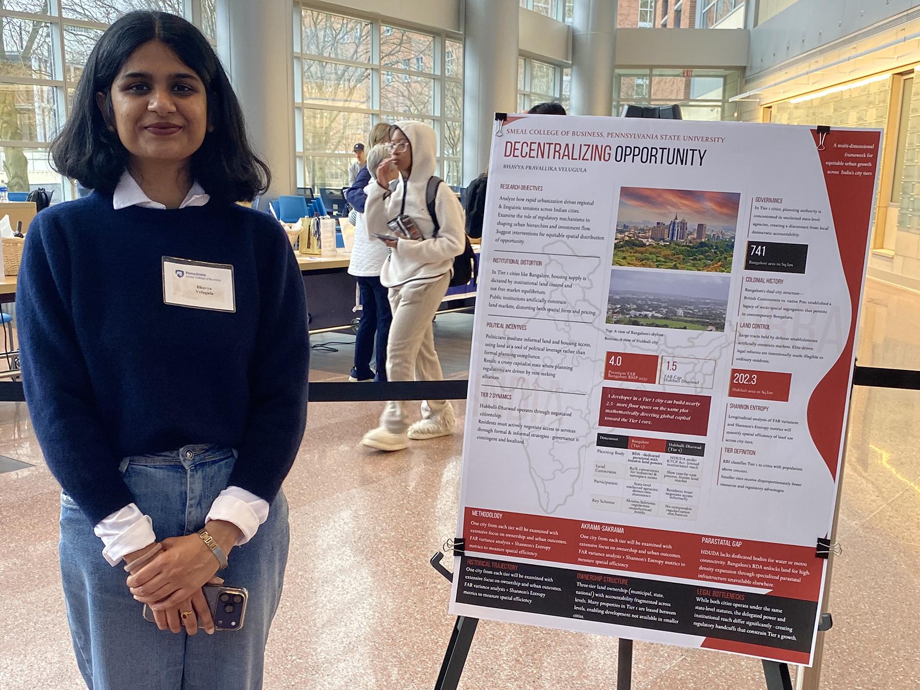 Bhavya Velugula stands next to a poster of her research.