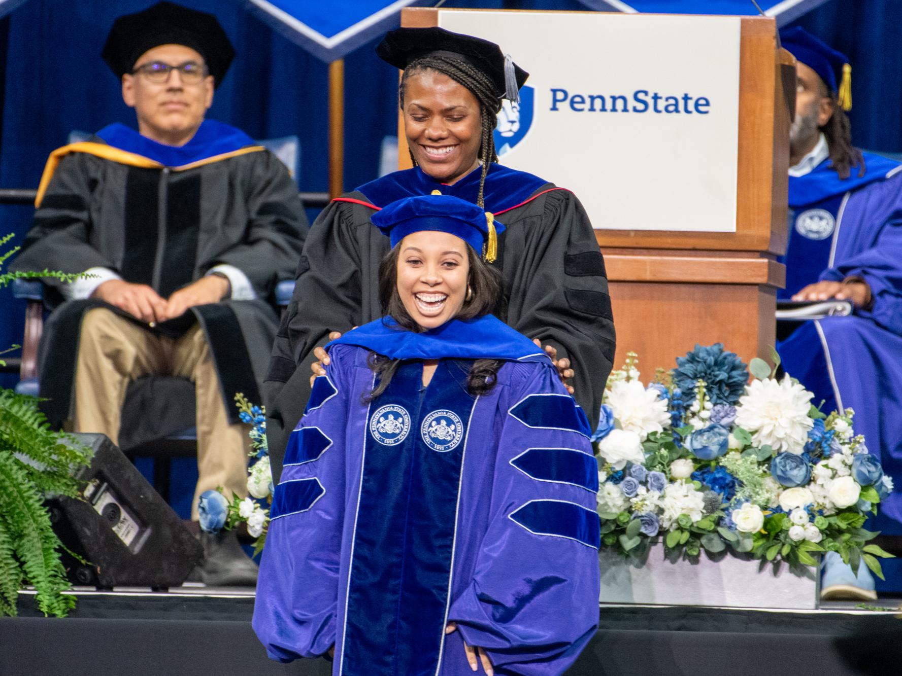 woman wearing doctoral regalia hooded on commencement state by faculty advisor