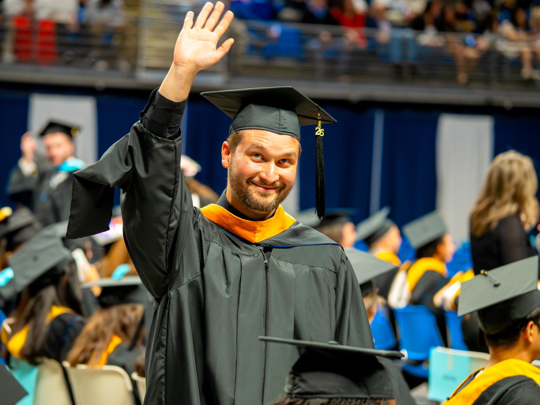person in regalia waves