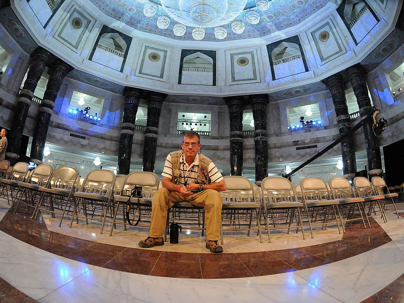 Man seated in a large room wearing khakis