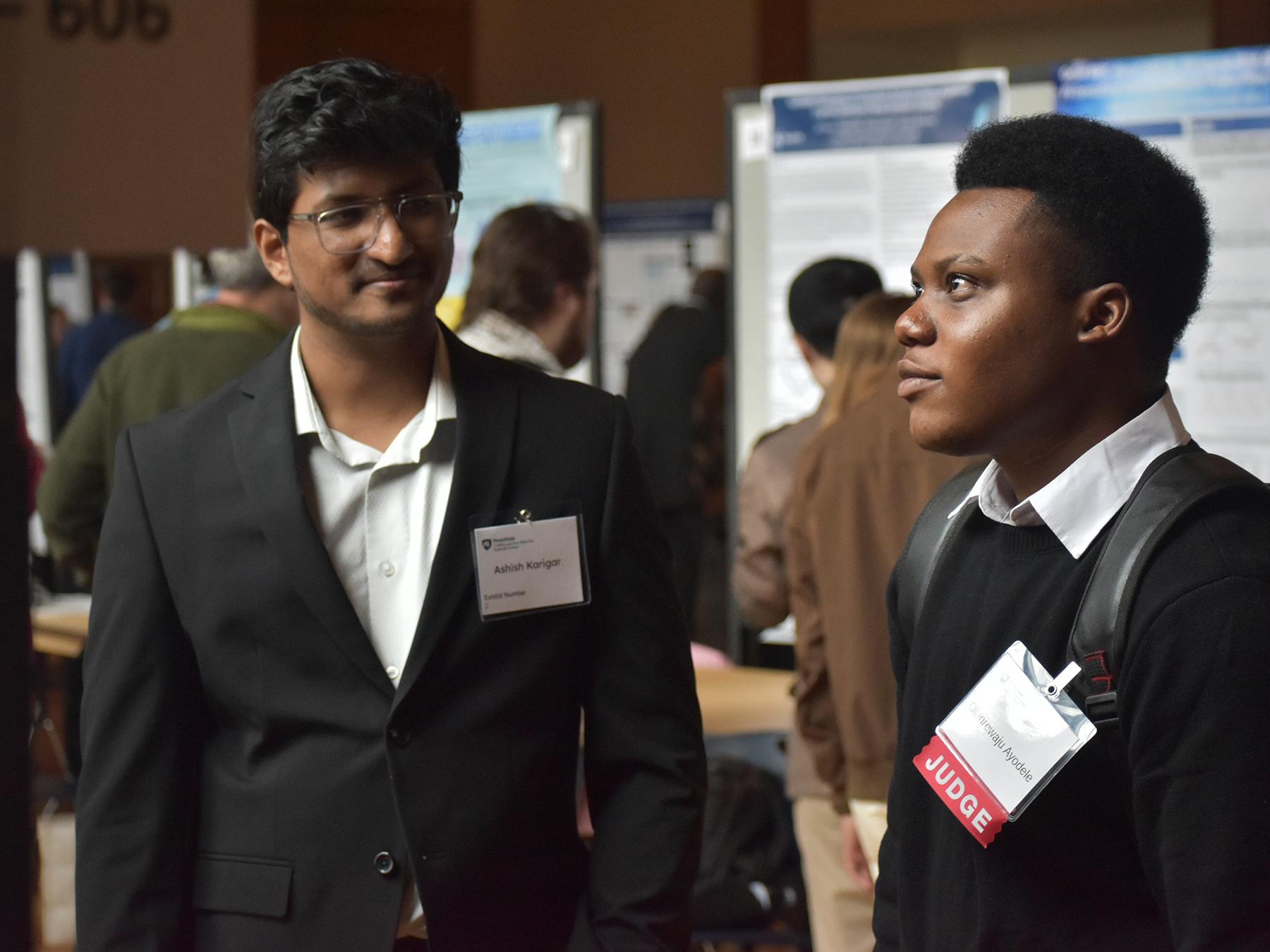 Olanrewaju Ayodele looks at another student poster during the Graduate Exhibition