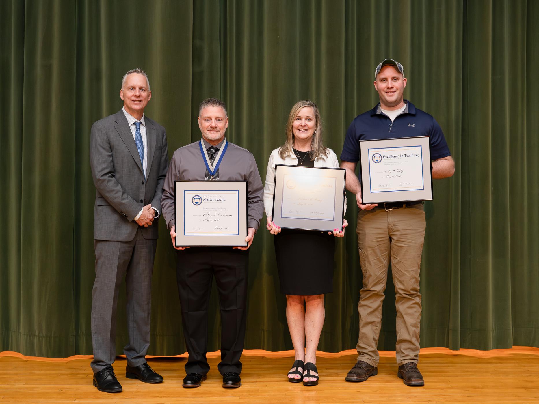 A group of people stand holding their awards