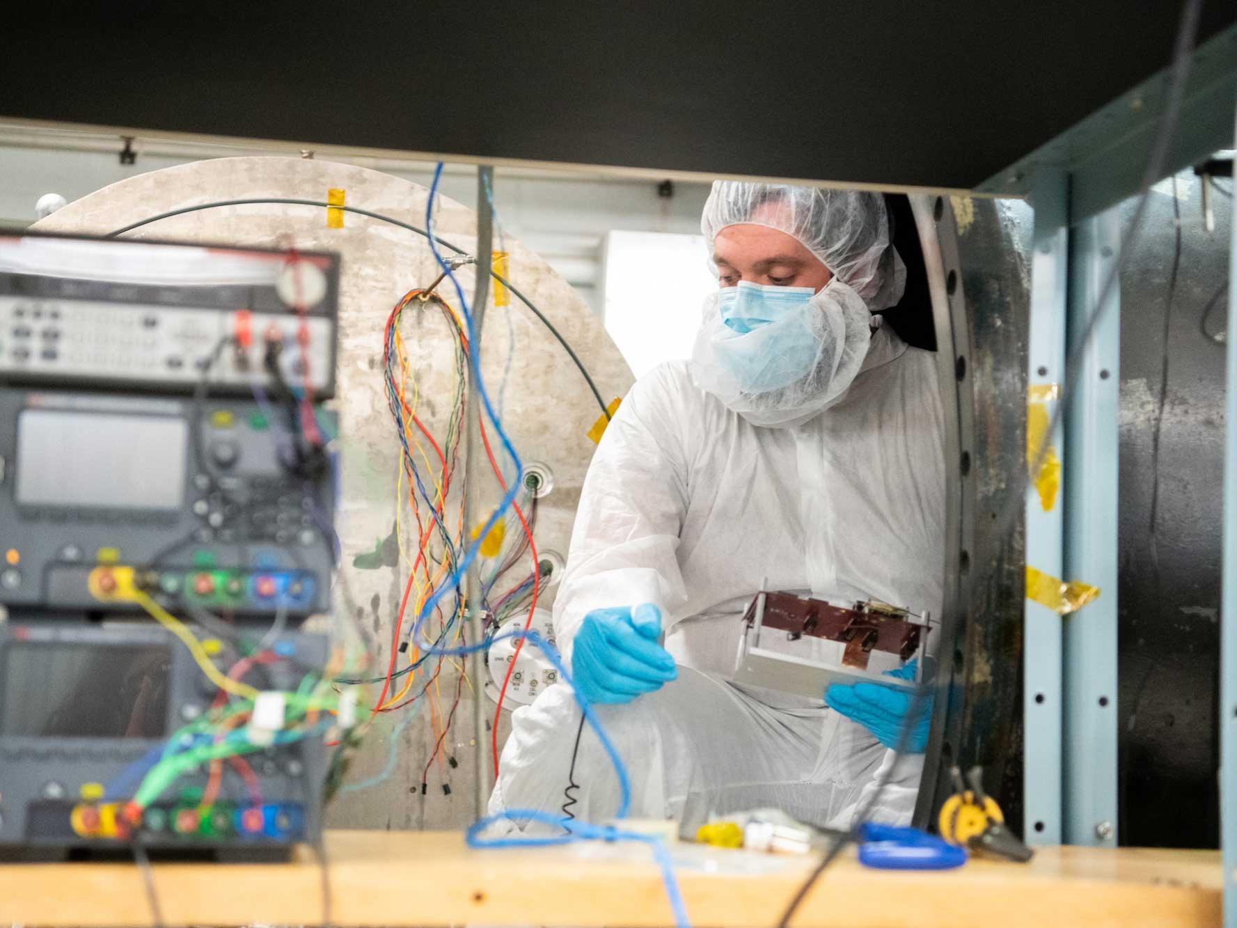 man in white static suit and mask handles electronics