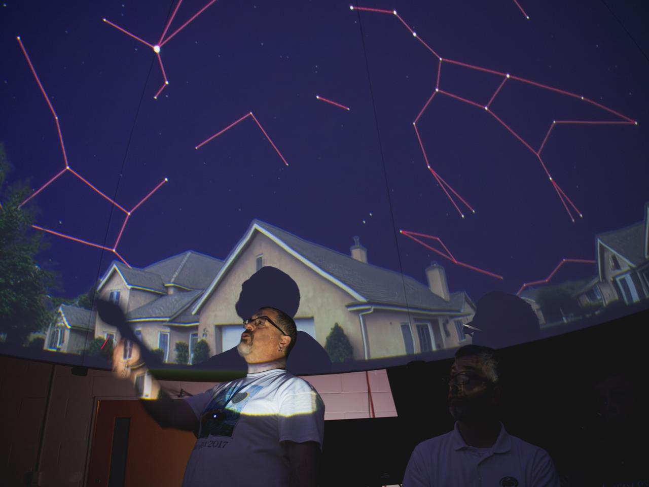 Chris Palma points to domed ceiling with projected constellations