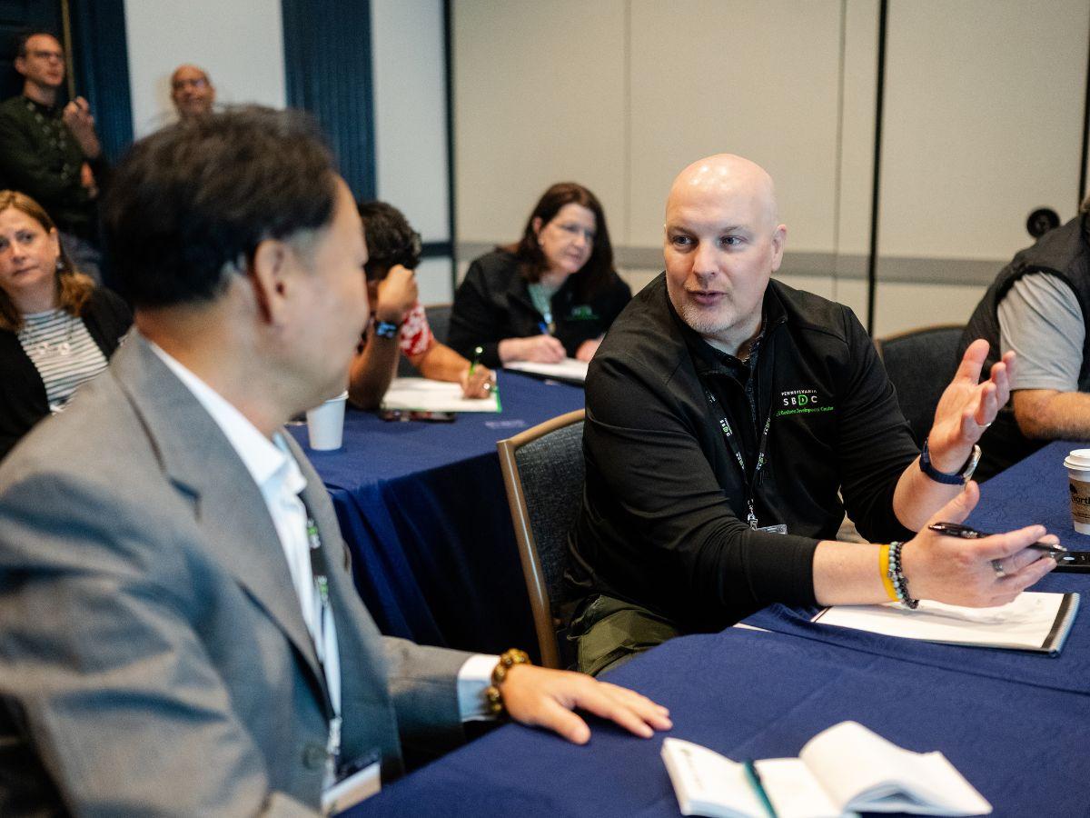Conference participants engage in a small-group discussion during a session, sharing ideas and taking notes.