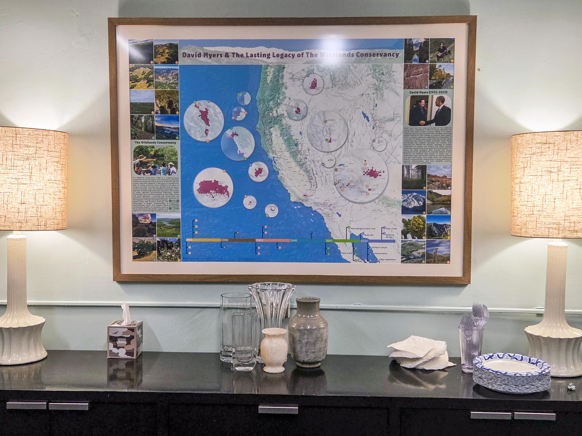 Wall-mounted map showcasing conservation projects, flanked by two lamps on a dark cabinet.