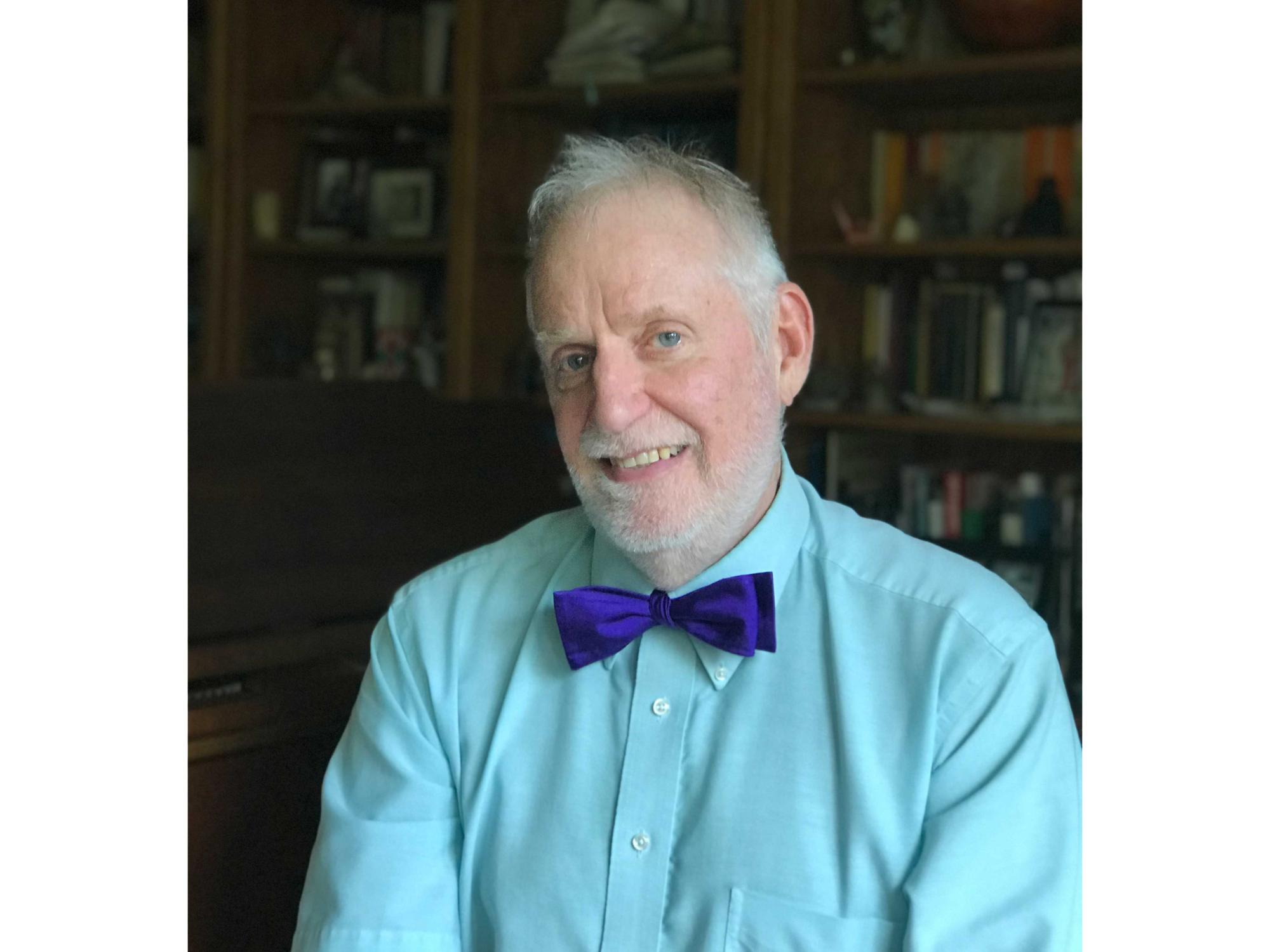 Don Schneider wearing bow tie in front of bookshelf