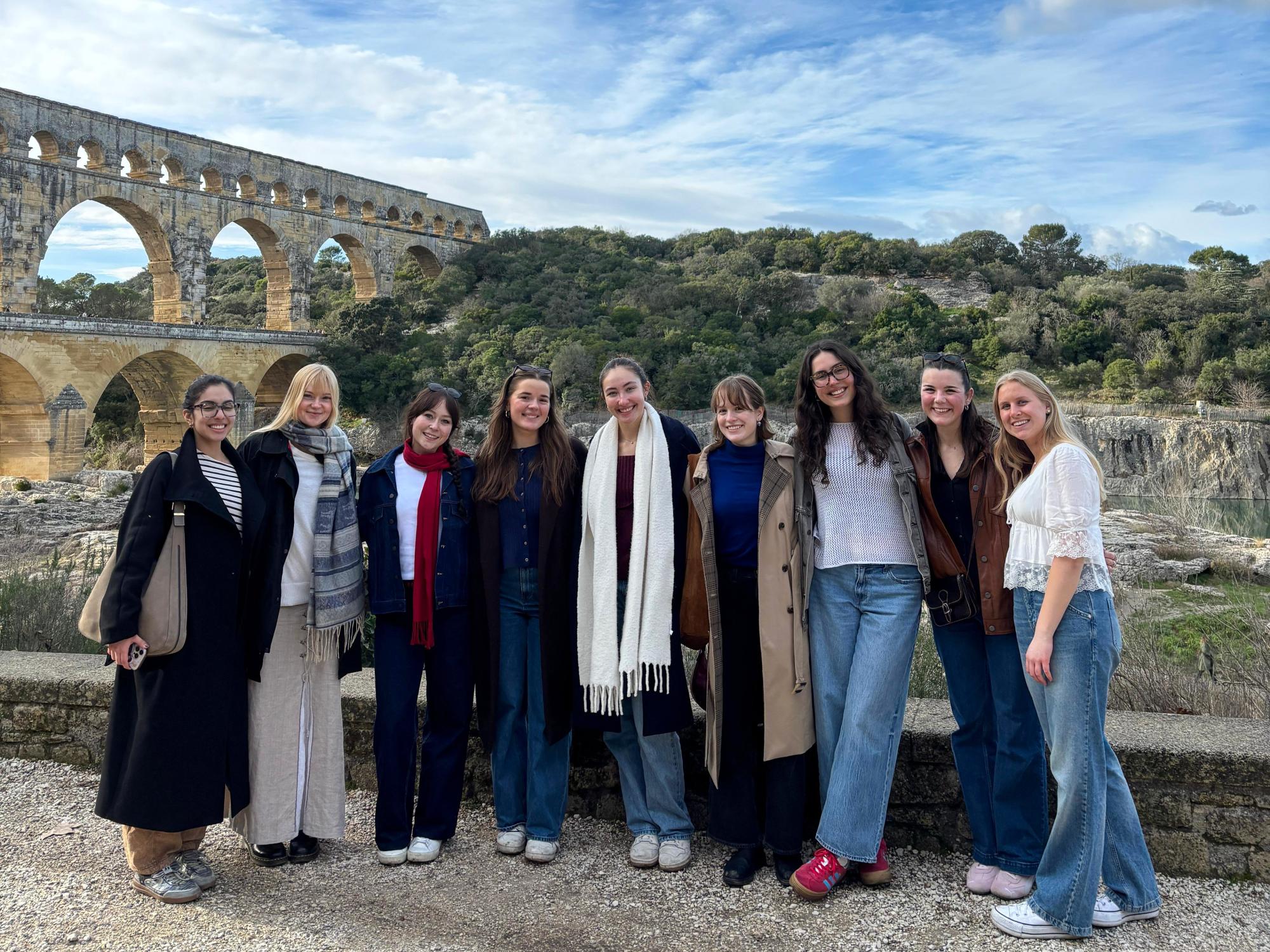Jenna Guarrera and seven other college students pose for a photo with the Pont du Gard and the French hillside behind them.
